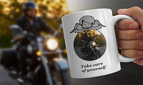 White mug with angel graphic and motorbike photo, labeled “Take care of yourself” — held in hand