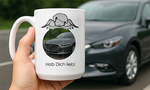White mug with angel graphic and Mazda car photo, labeled “Hab Dich lieb!” — held in front of parked car