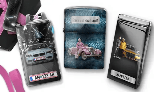 Three metal lighters featuring personalized designs. The left lighter shows a city skyline and a couple beside a car with 'BESTE OMA DER WELT'. The middle lighter depicts a pink vintage car with 'HAB DICH LIEB OMA' above. The right lighter displays a blue car and a license plate. Pink ribbons add a gift-like context.