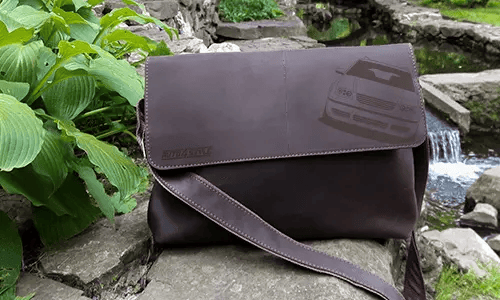 schwarze ledertasche auf dem Stein neben den Busch ledertasche schwarz