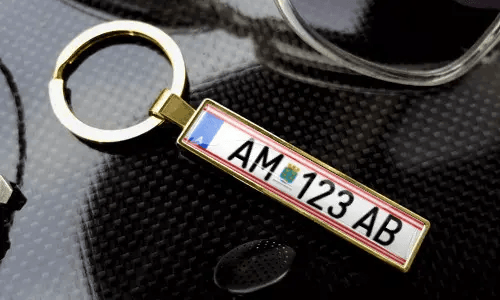 Gold license plate keychain displays engraved text in a polished metal frame