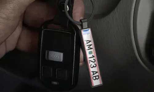 Llavero plateado de placa de matrícula cuelga de las llaves del coche dentro del vehículo