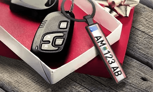 Autosleutelhanger met gepersonaliseerd kentekenlabel, naast de autosleutel/afstandsbediening