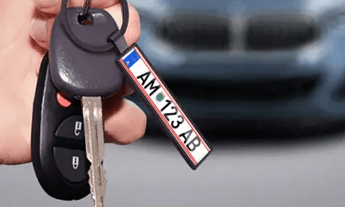 Black license plate keychain hangs from car keys in everyday use