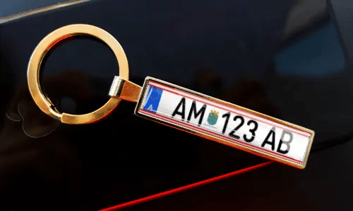 Porte-clés plaque d’immatriculation attaché à des clés dans la poche, avec une voiture en arrière-plan