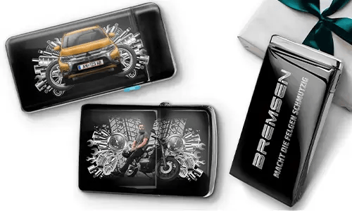 Elegante Geschenkboxen mit einem blauen Auto und einem Biker, umgeben von metallischen Zahnrädern. Eine Box trägt den Text „BREMSEN Macht Die Regeln Schmutzig“, was einen dynamischen, kantigen Ton hinzufügt.