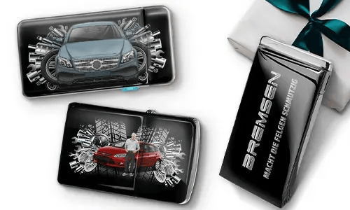 Drei elegante schwarze Geldbörsen mit Bildern von Autos und Zahnrädern, platziert neben einer Geschenkbox. Auf einer steht „Bremsen“. Das Design ist dynamisch und modern.