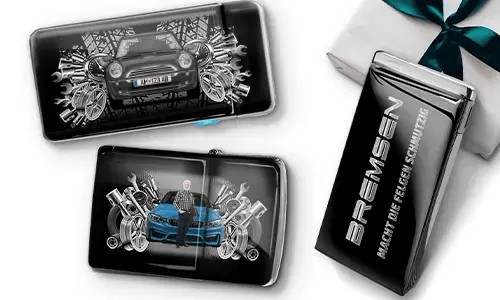 Three automotive-themed items featuring car illustrations and machinery motifs, arranged with a gift box tied with a green ribbon on the side.