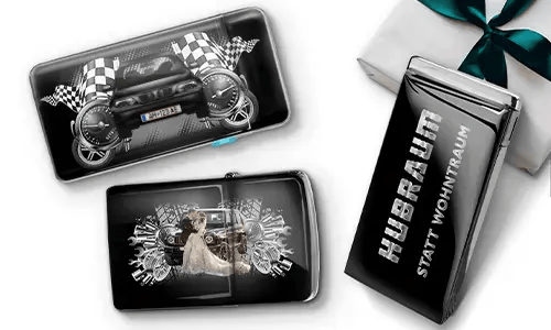 Three black wallets with car-themed designs and checkered flags, set against a white background. One shows a car with wheels, another features a couple, and one has 