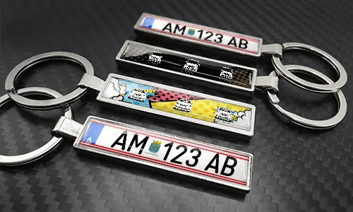 Comic-style license plate keychains arranged on a carbon-textured surface with colorful car graphics