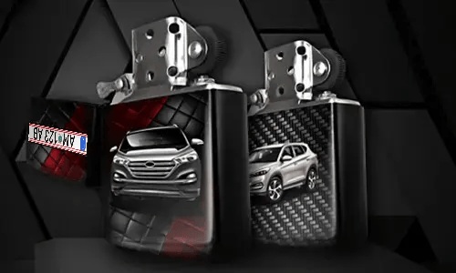 Two metallic lighters with silver SUV designs: one front view on tread background, one side view with carbon texture, small rectangular object in corner
